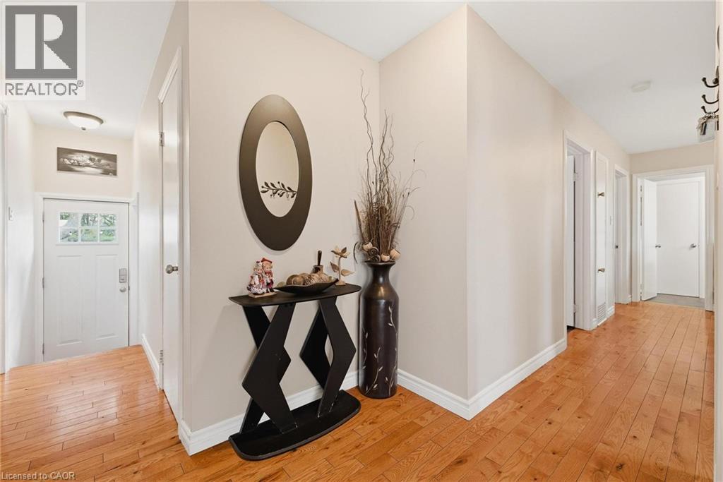 Hallway with wood-finish flooring, light neutral wall color, white baseboards, and multiple doorways - 120 Elgin Crescent, Waterloo, ON - Indoor Photo Showing Other Room