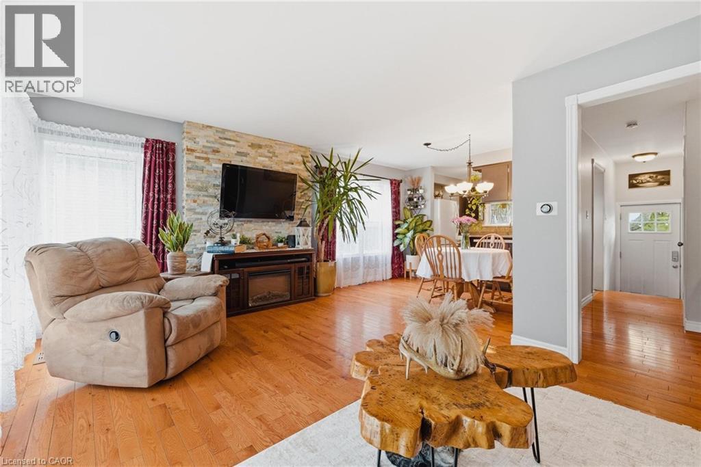 Living area featuring wood-finish flooring, a stacked stone accent wall, and an electric fireplace - 120 Elgin Crescent, Waterloo, ON - Indoor Photo Showing Living Room
