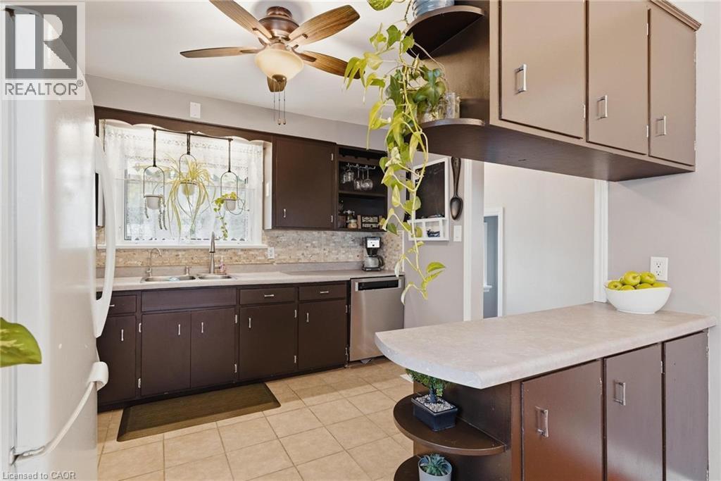 Kitchen with brown cabinetry, light-toned countertops, and a tiled backsplash - 120 Elgin Crescent, Waterloo, ON - Indoor Photo Showing Kitchen