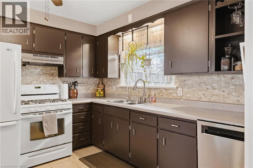 Kitchen featuring brown cabinetry, light-toned countertops, and a tiled backsplash - 120 Elgin Crescent, Waterloo, ON - Indoor Photo Showing Kitchen With Double Sink