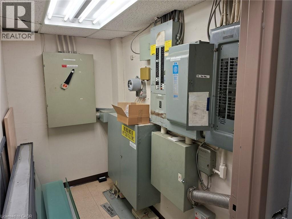 Utility room featuring multiple electrical panels, conduit-covered wiring, and fluorescent ceiling lights - 920 Sheldon Court, Burlington, ON