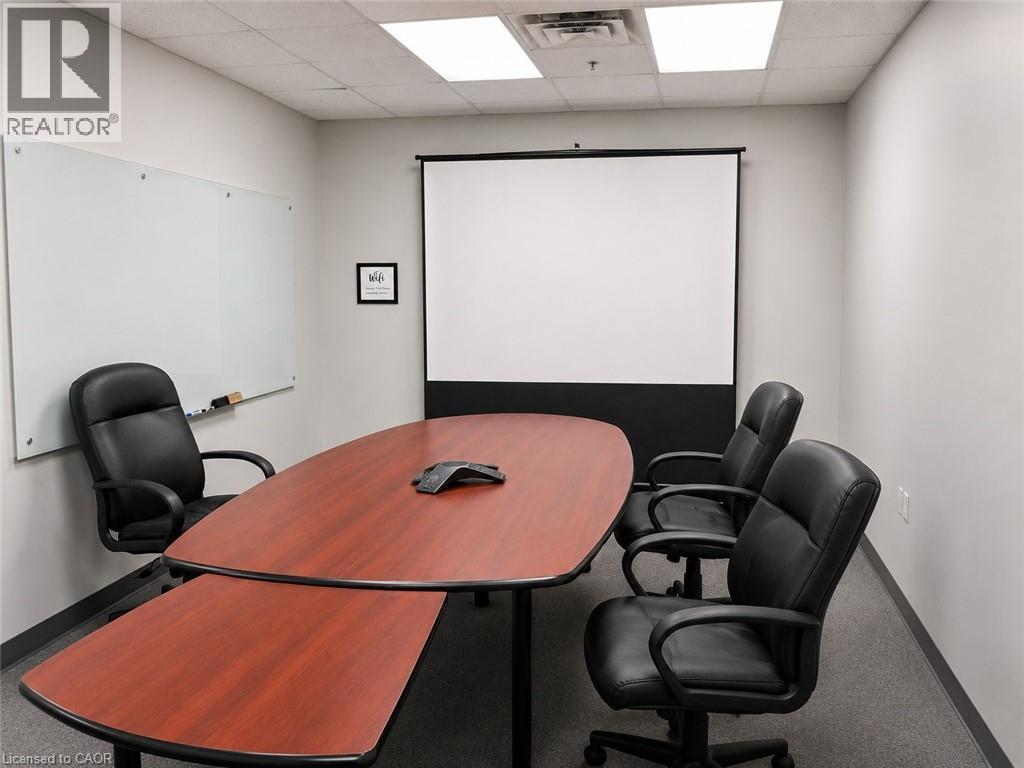 Conference room featuring a large wood-finish table, wall-mounted projector screen, and a glass whiteboard - 920 Sheldon Court, Burlington, ON