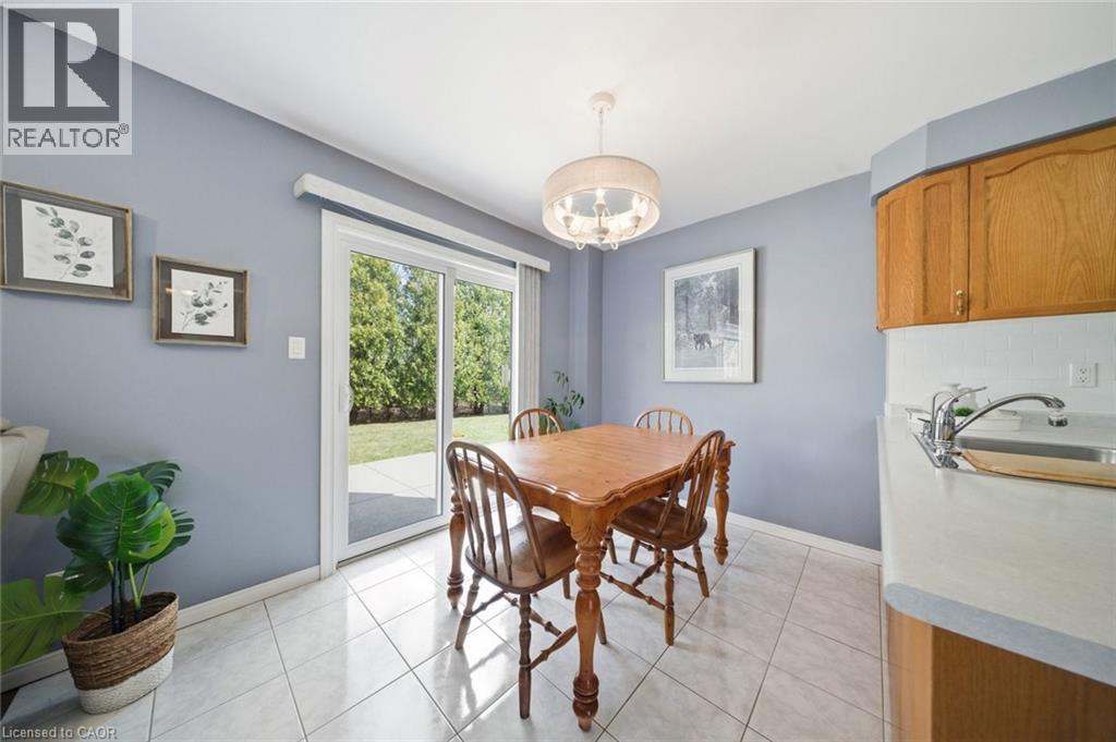 Dining area with direct patio access, featuring light-toned tile flooring and a suspended drum chandelier - 200 Morrison Drive, Caledonia, ON - Indoor Photo Showing Dining Room