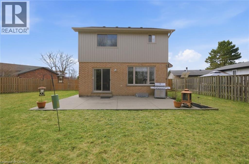 Expansive backyard featuring a large concrete patio, brick and siding exterior, and a privacy fence - 200 Morrison Drive, Caledonia, ON - Outdoor