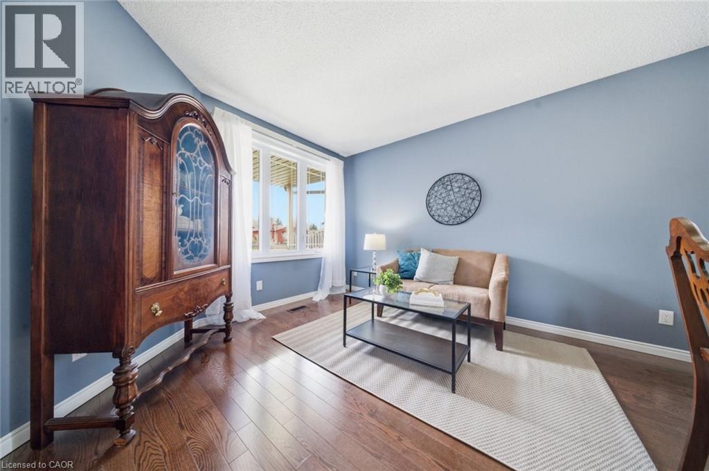 Spacious room featuring wood-finish flooring, light blue painted walls, white baseboards, and a white popcorn ceiling - 200 Morrison Drive, Caledonia, ON - Indoor Photo Showing Living Room