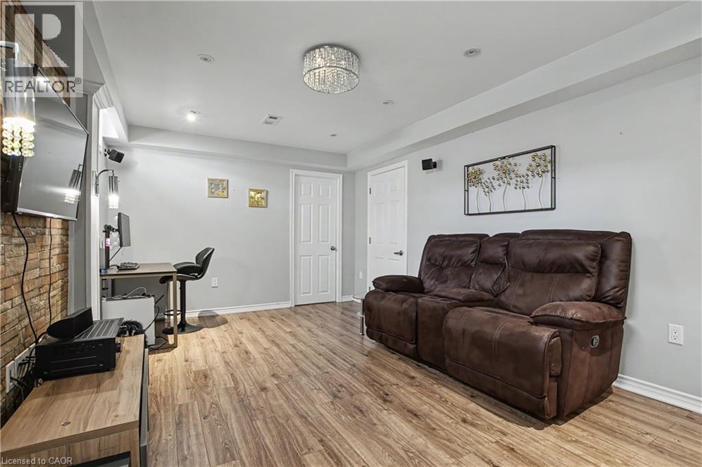 Spacious interior featuring wood-finish flooring, light gray walls, white trim, and a decorative crystal chandelier - 60 Postmaster Drive, Kitchener, ON - Indoor