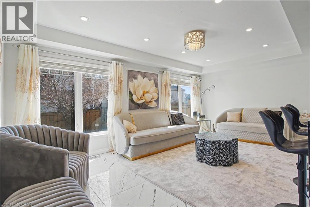 Expansive living area featuring large windows, a tray ceiling with recessed lighting, a decorative chandelier, and polished tile flooring - 60 Postmaster Drive, Kitchener, ON - Indoor Photo Showing Living Room