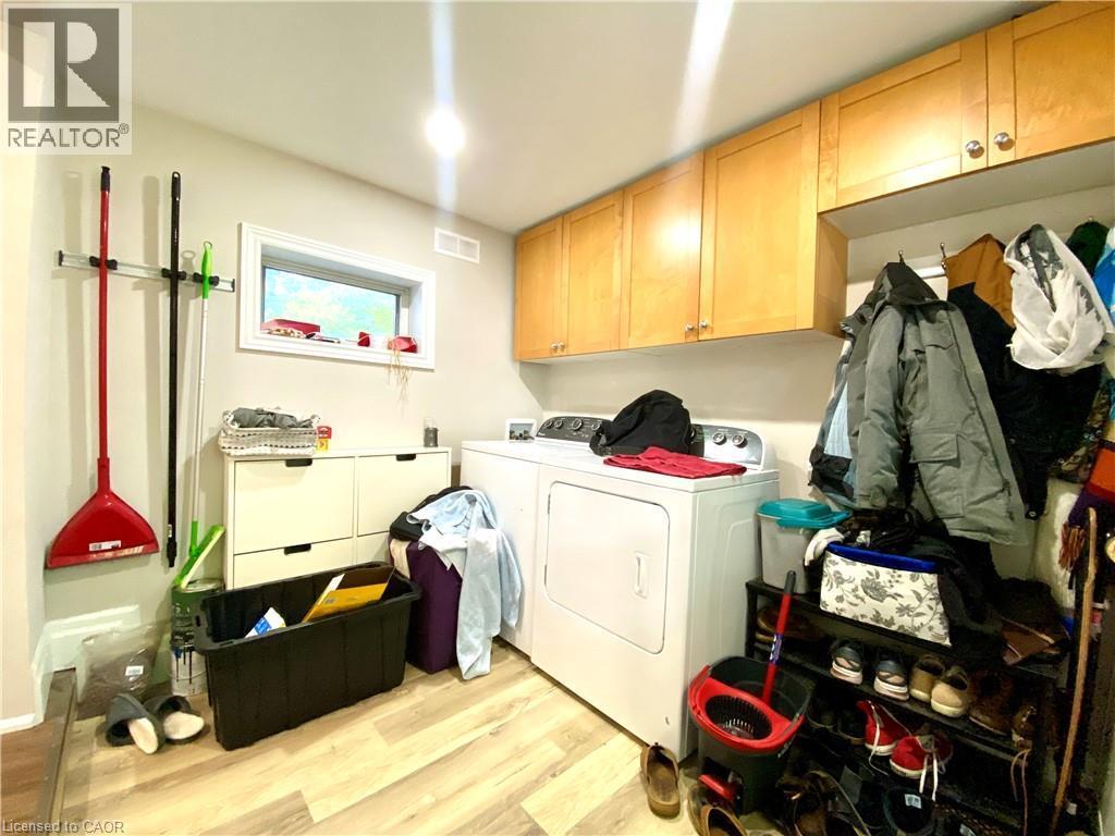 Laundry area featuring wood-finish flooring, a window, and overhead cabinetry - 358 Dundas Street E, Hamilton, ON - Indoor Photo Showing Laundry Room