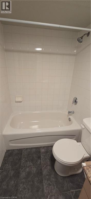 Bathroom featuring a white tub, chrome fixtures, white subway tile surround, and dark-toned floor tiles - 274 E Highland Road E Unit# 10, Kitchener, ON - Indoor Photo Showing Bathroom