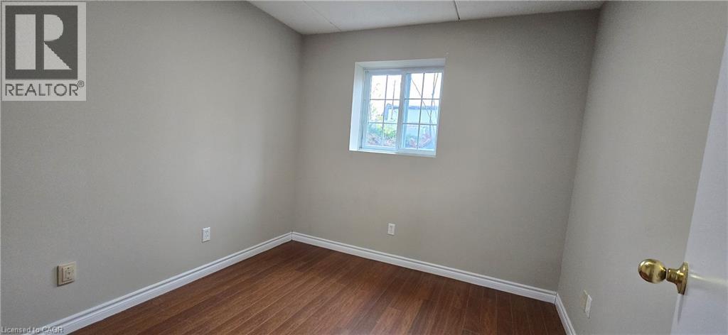 Room featuring wood-finish flooring, light neutral wall paint, and white baseboards - 274 E Highland Road E Unit# 10, Kitchener, ON - Indoor Photo Showing Other Room