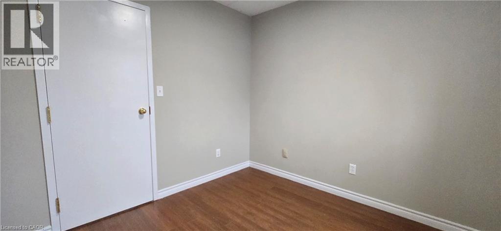 Room featuring wood-finish flooring, light neutral wall paint, and white baseboards - 274 E Highland Road E Unit# 10, Kitchener, ON - Indoor Photo Showing Other Room