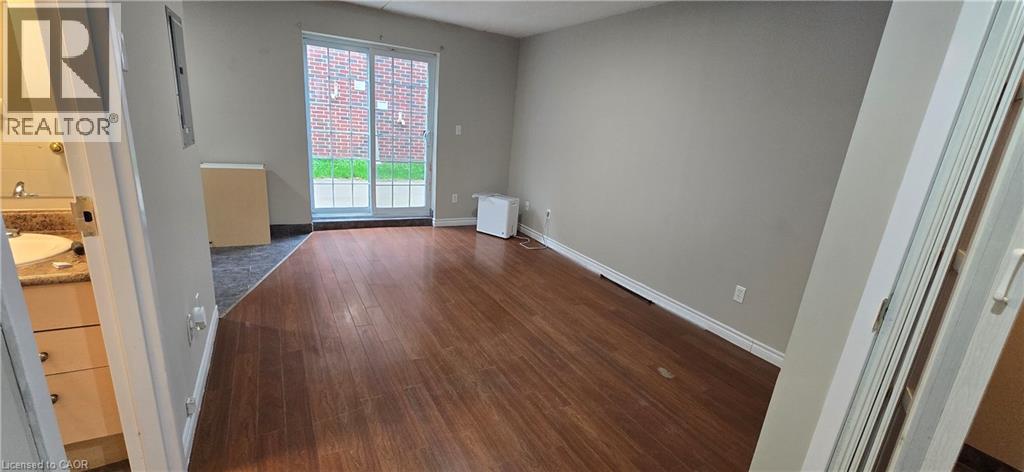 Spacious room featuring wood-finish flooring, neutral wall tones, and white baseboards - 274 E Highland Road E Unit# 10, Kitchener, ON - Indoor Photo Showing Other Room
