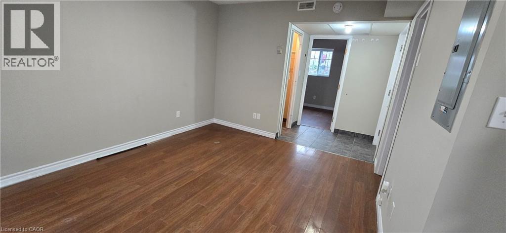 Spacious interior featuring wood-finish flooring, light grey walls, white baseboards, and a white ceiling - 274 E Highland Road E Unit# 10, Kitchener, ON - Indoor Photo Showing Other Room