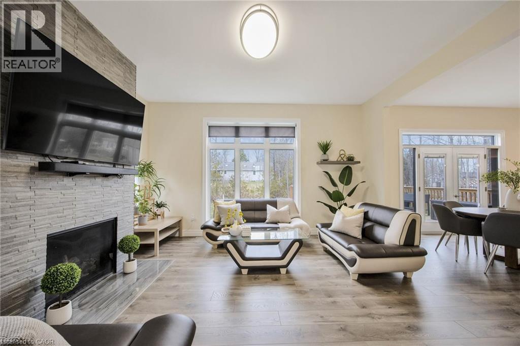 Spacious living area featuring light-toned walls, wood-finish flooring, and a stone-clad fireplace - 6 Dorothys Drive, Oro-Medonte, ON - Indoor Photo Showing Living Room With Fireplace