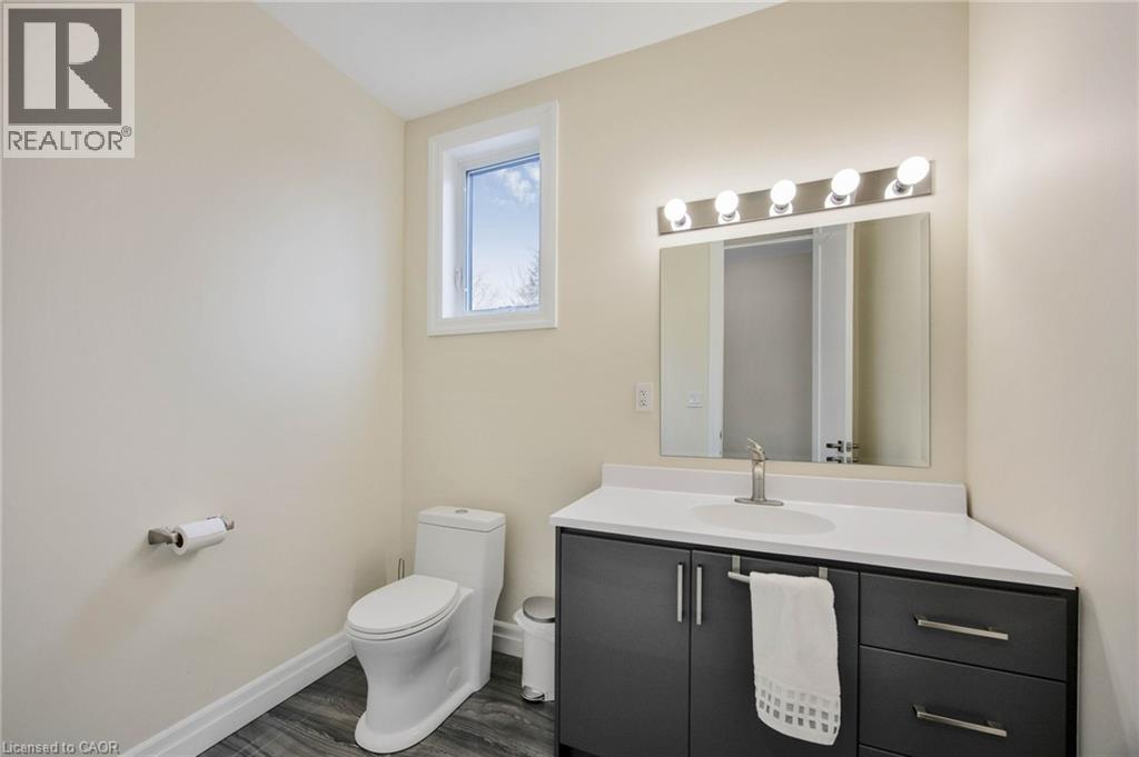 Bathroom featuring wood-finish flooring, a contemporary vanity with dark cabinetry, a white countertop, and a rectangular undermount sink with a brushed nickel faucet - 6 Dorothys Drive, Oro-Medonte, ON - Indoor Photo Showing Bathroom