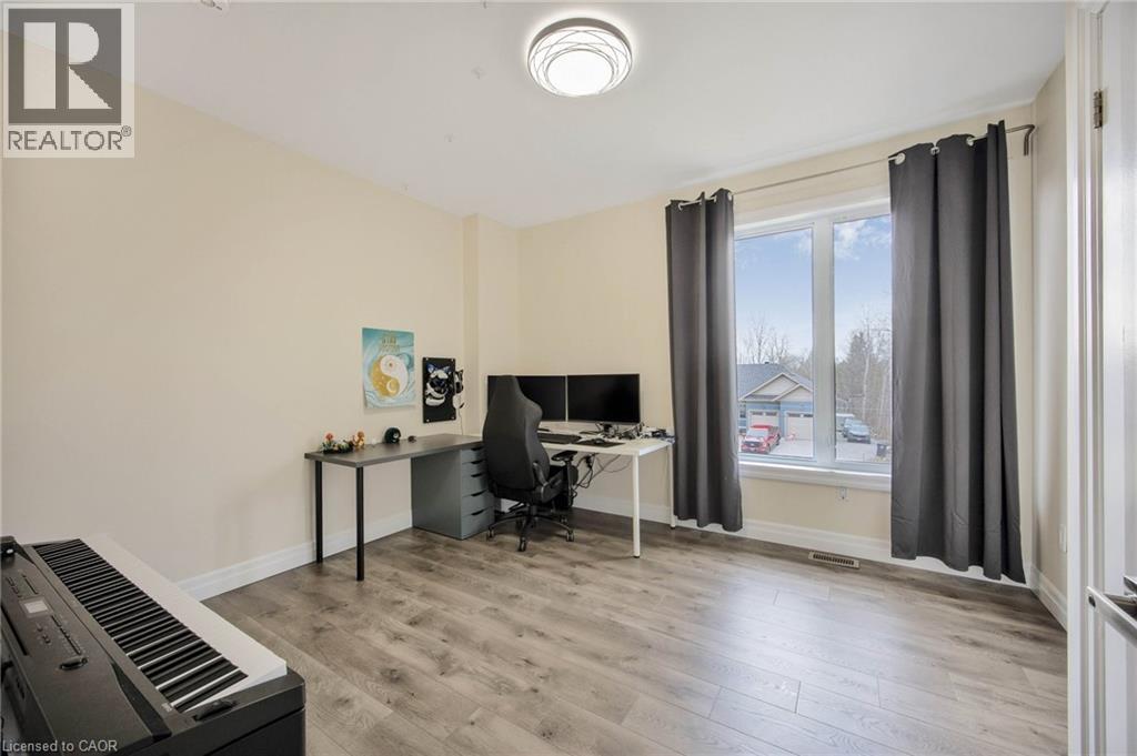 Spacious room featuring wood-finish flooring, light-colored walls, a large window with white trim, and a modern ceiling light fixture - 6 Dorothys Drive, Oro-Medonte, ON - Indoor