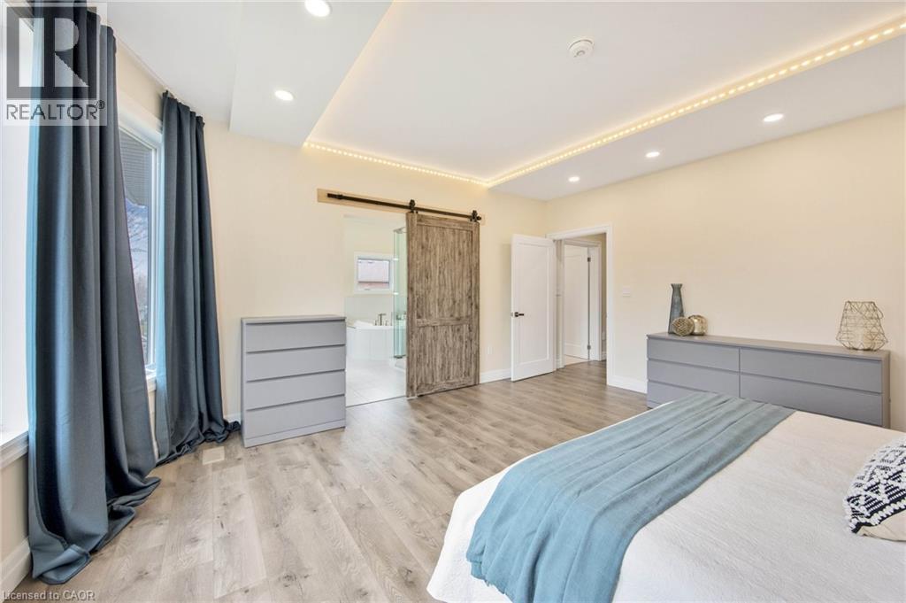 Expansive room featuring wood-finish flooring, recessed lighting, and a barn door entry to an adjoining space - 6 Dorothys Drive, Oro-Medonte, ON - Indoor Photo Showing Bedroom