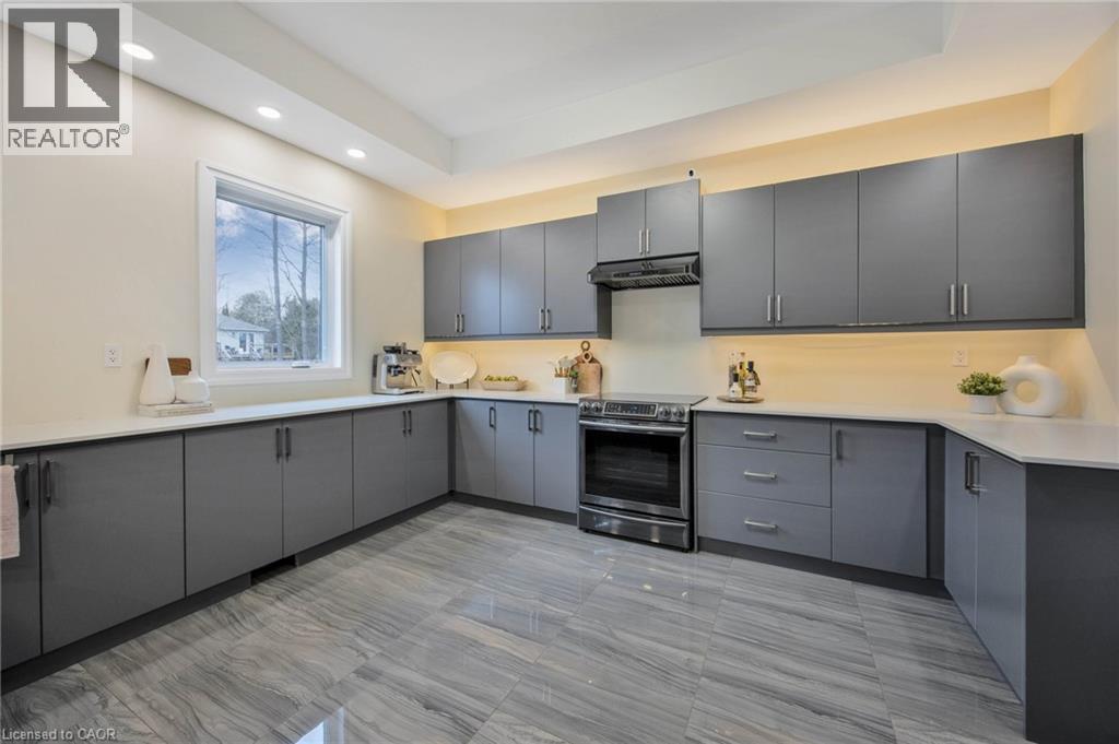 Contemporary kitchen featuring extensive gray cabinetry, light countertops, stainless steel range and hood, under-cabinet lighting, and large format tiled flooring - 6 Dorothys Drive, Oro-Medonte, ON - Indoor Photo Showing Kitchen