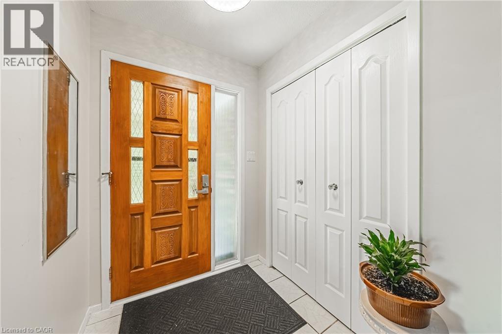 Front entry featuring a paneled wood-finish door with decorative glass inserts and a frosted sidelight - 235 Larch Street, Hamilton, ON - Indoor Photo Showing Other Room