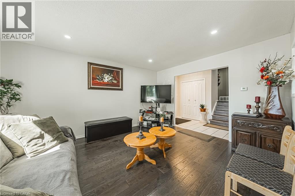 Living area featuring dark wood-finish flooring, recessed ceiling lighting, and a neutral wall color - 235 Larch Street, Hamilton, ON - Indoor Photo Showing Living Room