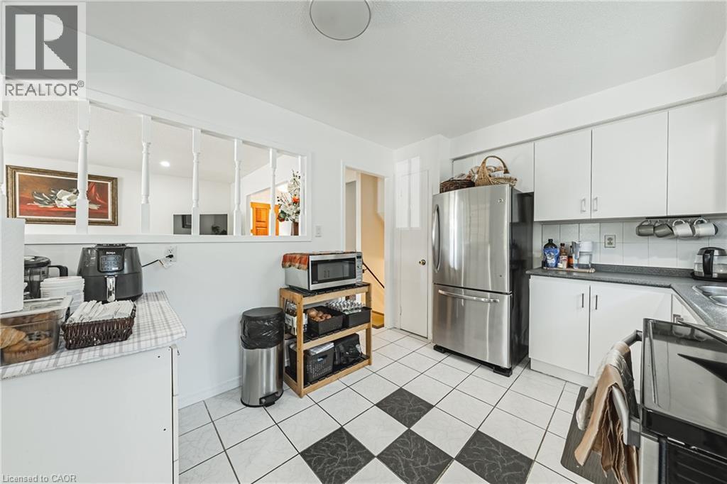 Kitchen featuring a checkerboard tile floor, white cabinetry, and a stainless steel refrigerator - 235 Larch Street, Hamilton, ON - Indoor Photo Showing Kitchen
