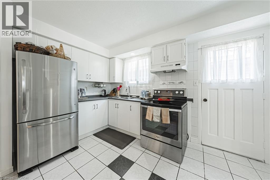 Kitchen featuring white cabinetry, stainless steel appliances, dark countertops, and a black and white checkered floor tile pattern - 235 Larch Street, Hamilton, ON - Indoor Photo Showing Kitchen