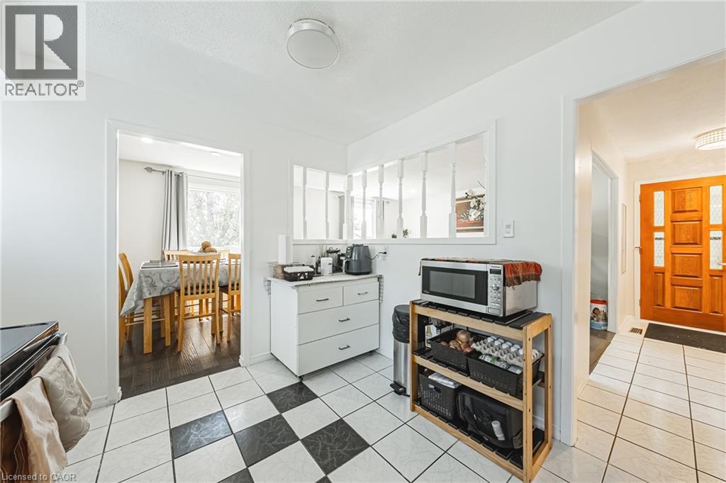 Kitchen area featuring checkerboard tile flooring, white cabinetry, and a decorative interior window - 235 Larch Street, Hamilton, ON - Indoor