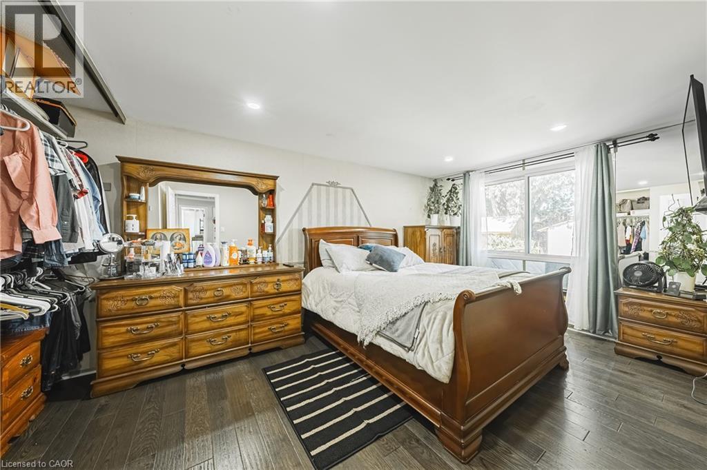 Bedroom featuring dark wood-finish flooring, recessed lighting, and a large window with natural light - 235 Larch Street, Hamilton, ON - Indoor Photo Showing Bedroom