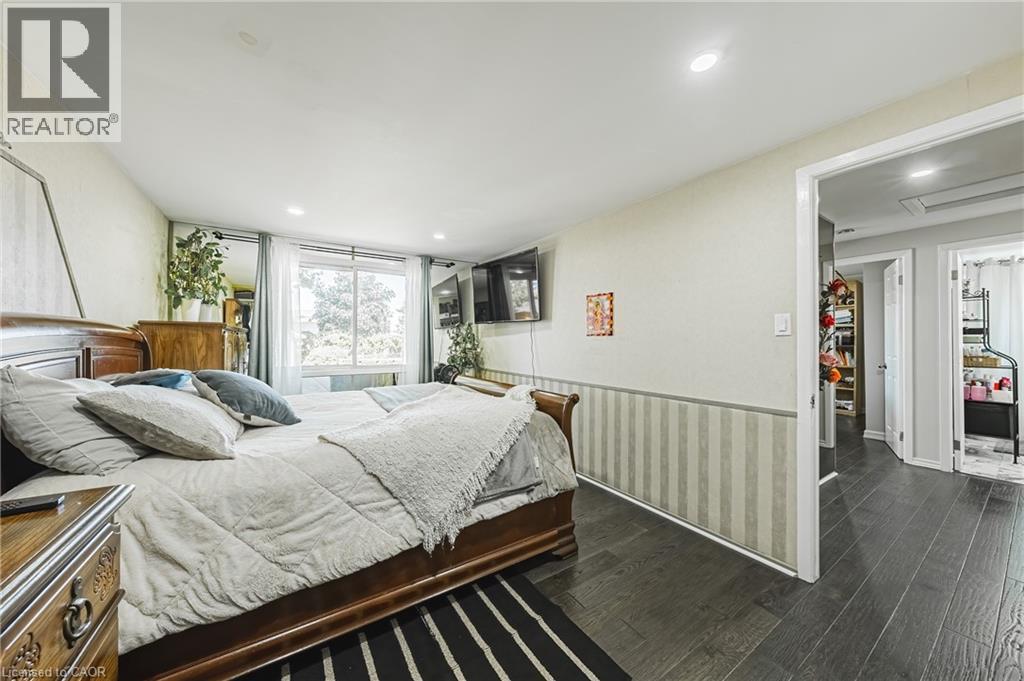 Spacious room featuring dark wood-finish flooring, recessed lighting, and a large window - 235 Larch Street, Hamilton, ON - Indoor Photo Showing Bedroom