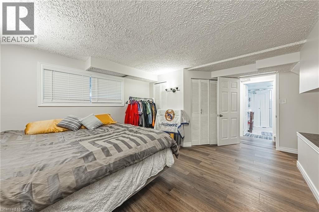 Spacious room featuring wood-finish flooring, white walls, and a textured ceiling - 235 Larch Street, Hamilton, ON - Indoor Photo Showing Bedroom