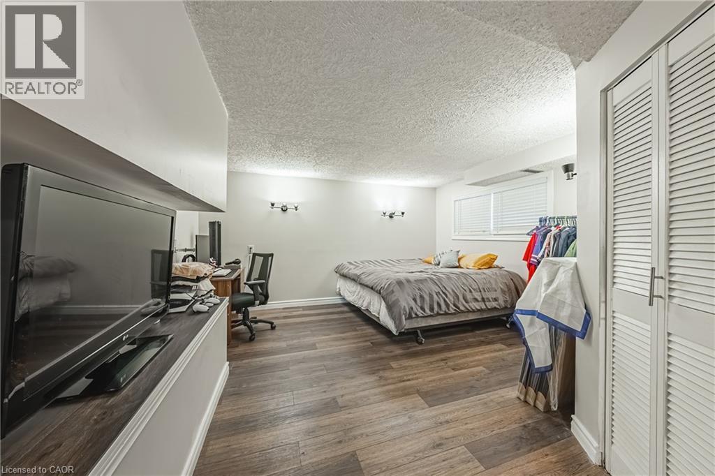 Spacious room featuring wood-finish flooring, white walls, and a textured ceiling - 235 Larch Street, Hamilton, ON - Indoor