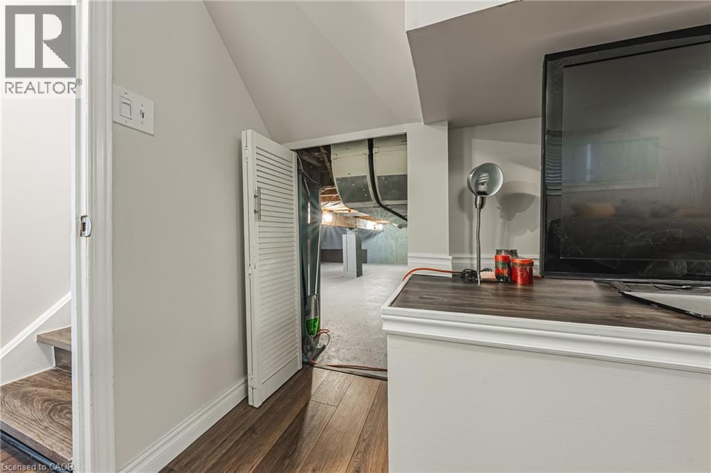 Finished wood-finish flooring extending into the stairwell, white baseboards, and neutral wall paint - 235 Larch Street, Hamilton, ON - Indoor