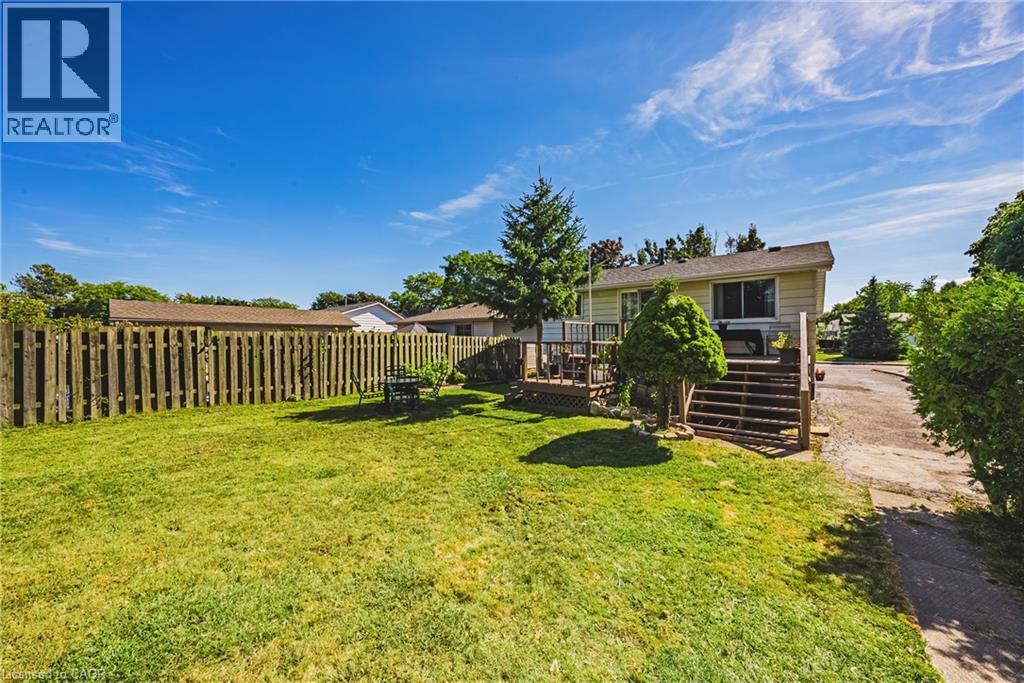 Expansive backyard featuring a lush lawn, privacy fencing, and a multi-level wood deck with stairs - 235 Larch Street, Hamilton, ON - Outdoor