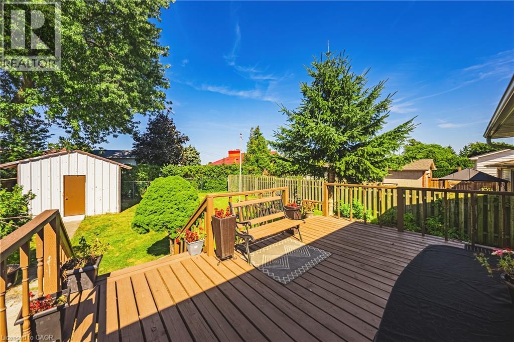 Expansive wood deck with natural wood railing overlooking a fenced yard - 235 Larch Street, Hamilton, ON - Outdoor With Deck Patio Veranda