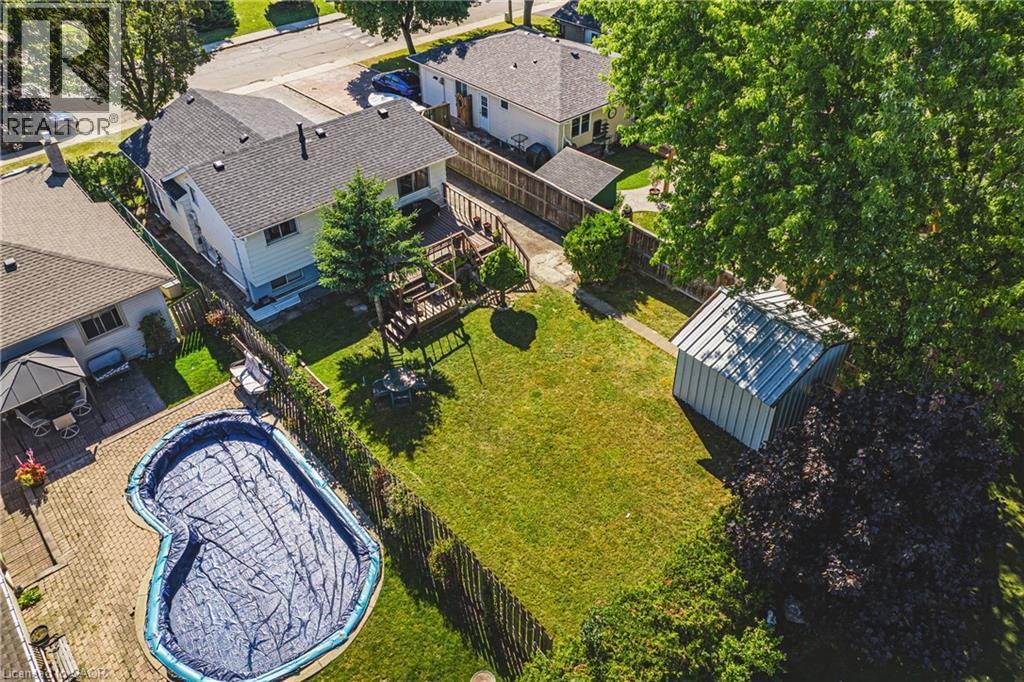 Spacious backyard featuring a kidney-shaped pool with a paved surround, a two-story wood deck, a manicured lawn, and a metal storage shed - 235 Larch Street, Hamilton, ON - Outdoor