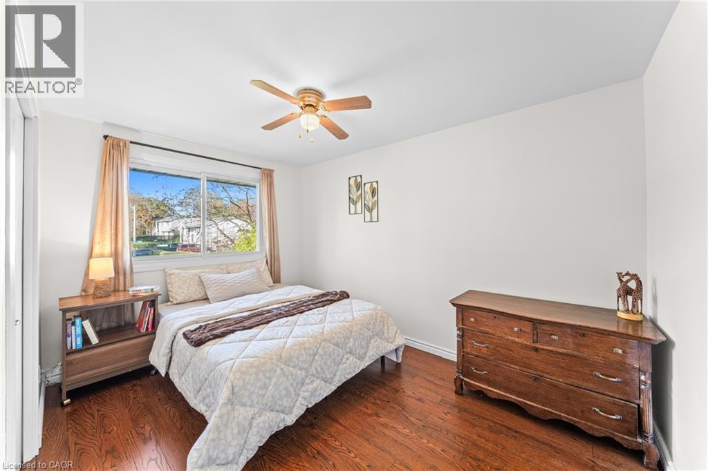 Bright bedroom featuring wood-finish flooring, a ceiling fan with integrated lighting, and white walls - 183 Harvard Road, Waterloo, ON - Indoor Photo Showing Bedroom
