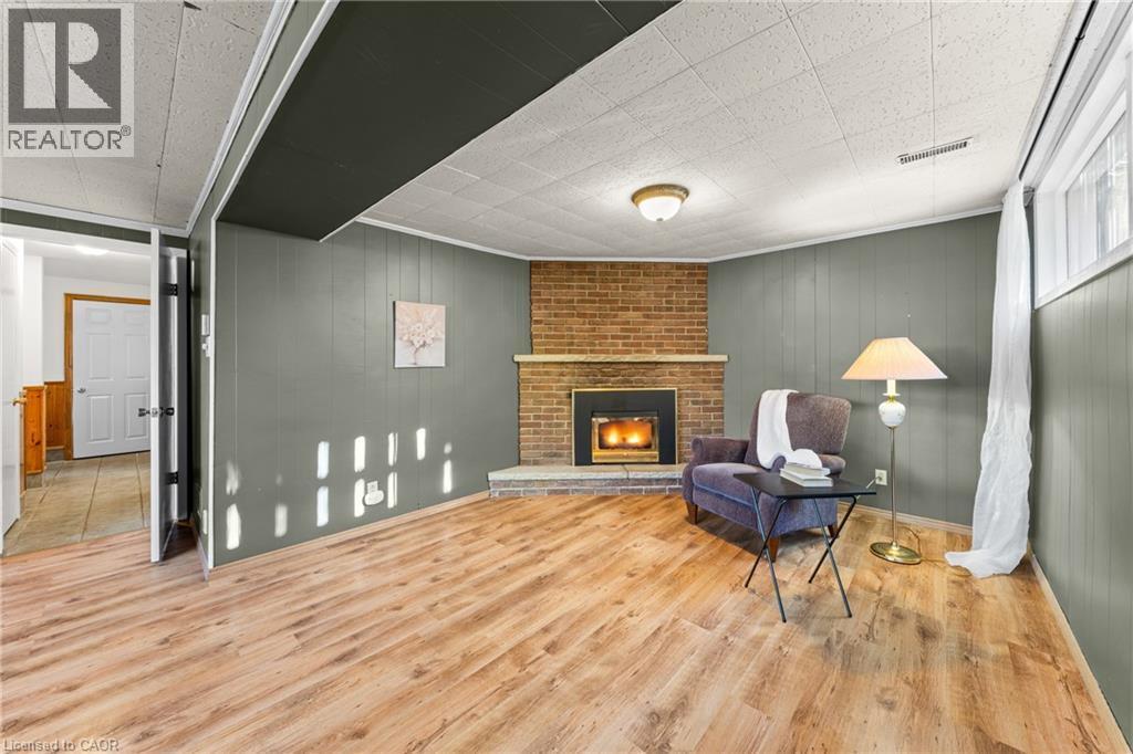 Spacious room featuring wood-finish flooring and paneling walls - 183 Harvard Road, Waterloo, ON - Indoor With Fireplace