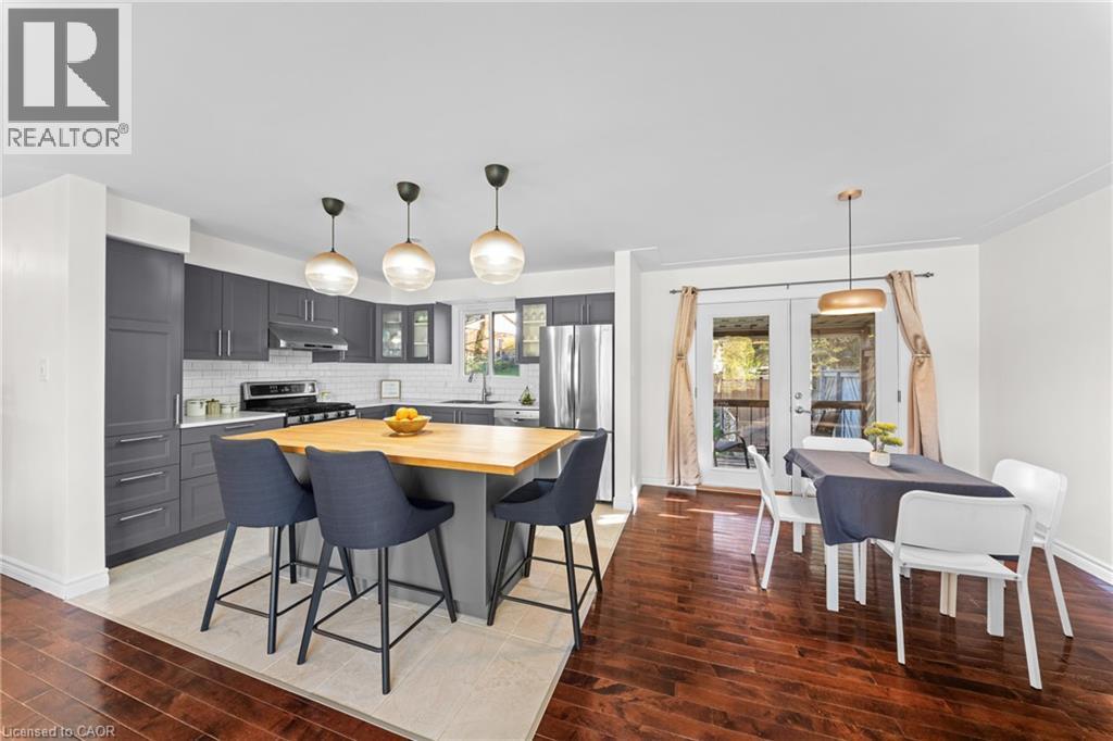 Kitchen featuring dark grey cabinetry, stainless steel appliances, a white subway tile backsplash, and a light wood-finish island - 183 Harvard Road, Waterloo, ON - Indoor Photo Showing Other Room