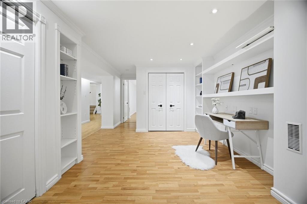 Bright interior hallway featuring wood-finish flooring, recessed lighting, built-in shelving, white paneled doors, and an integrated desk area - 1376 Royal Drive, Burlington, ON - Indoor Photo Showing Other Room