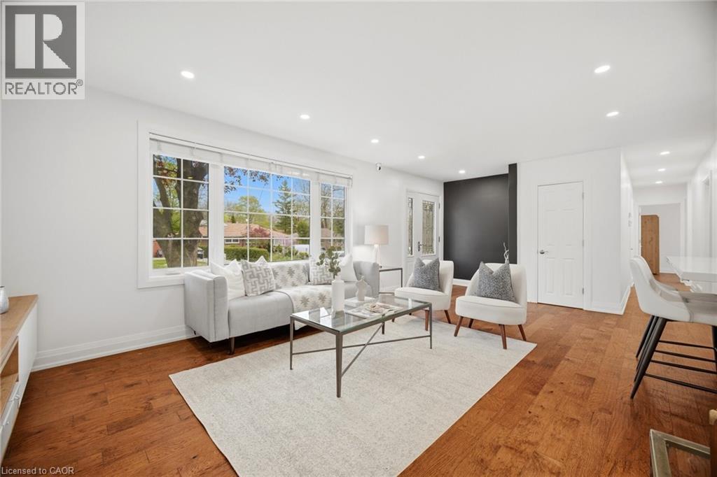 Spacious living area featuring large picture windows, wood-finish flooring, recessed lighting, a modern accent wall, and a bright white interior palette - 1376 Royal Drive, Burlington, ON - Indoor Photo Showing Living Room