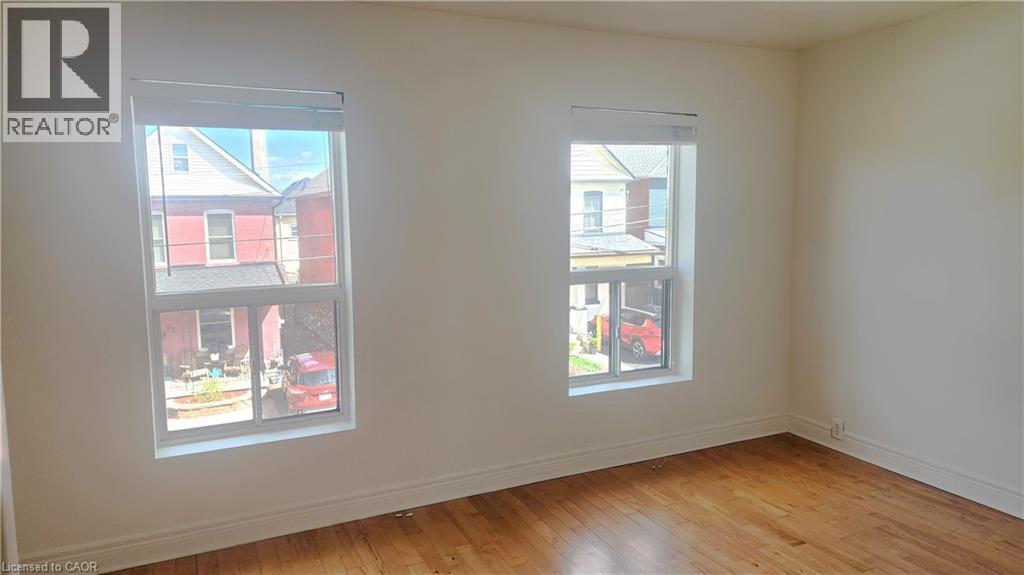 Room featuring two windows with white trim, wood-finish flooring, white walls, and white baseboards - 85 Oxford Street, Hamilton, ON - Indoor Photo Showing Other Room