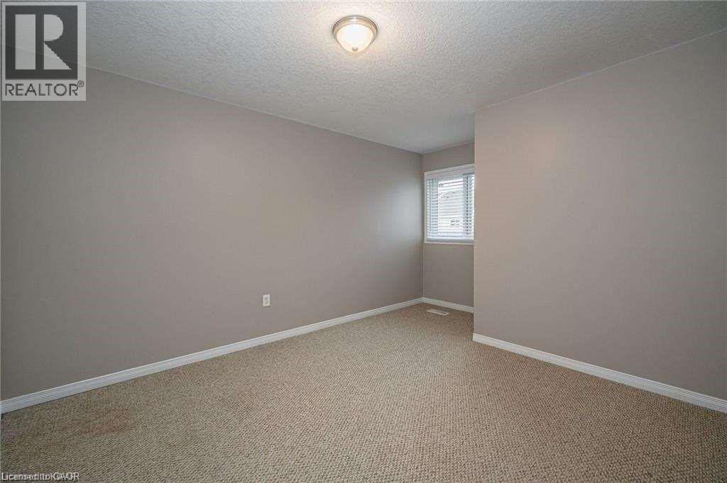 Neutral wall finishes, textured carpeting, and white baseboards - 27 Max Becker Drive, Kitchener, ON - Indoor Photo Showing Other Room