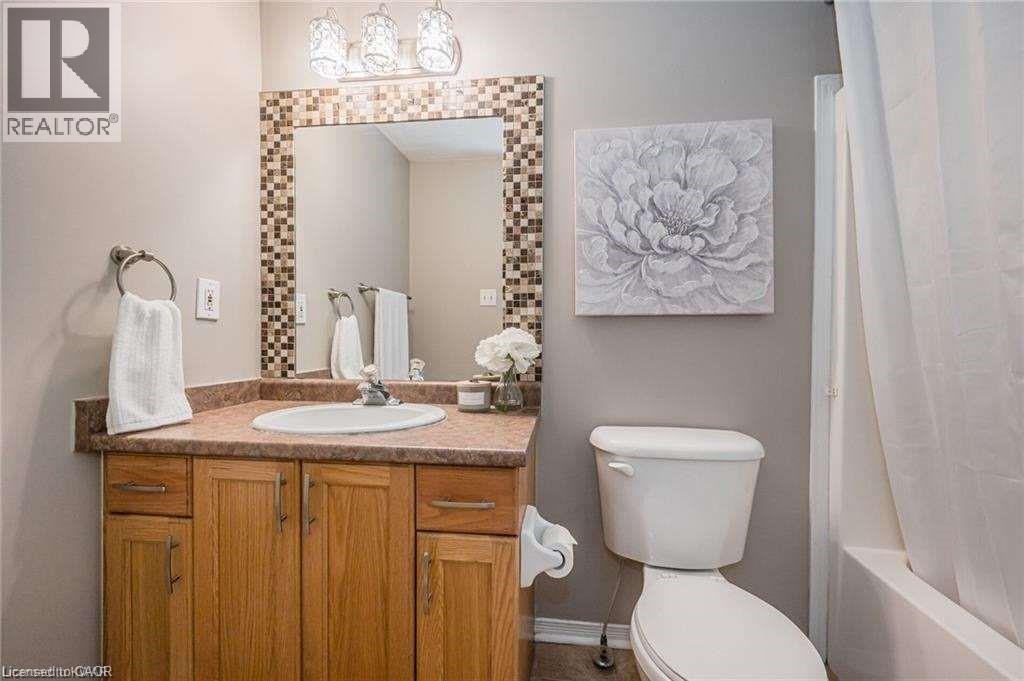 Bathroom featuring a light wood vanity with a built-in sink, a speckled countertop, and a mosaic-framed mirror - 27 Max Becker Drive, Kitchener, ON - Indoor Photo Showing Bathroom