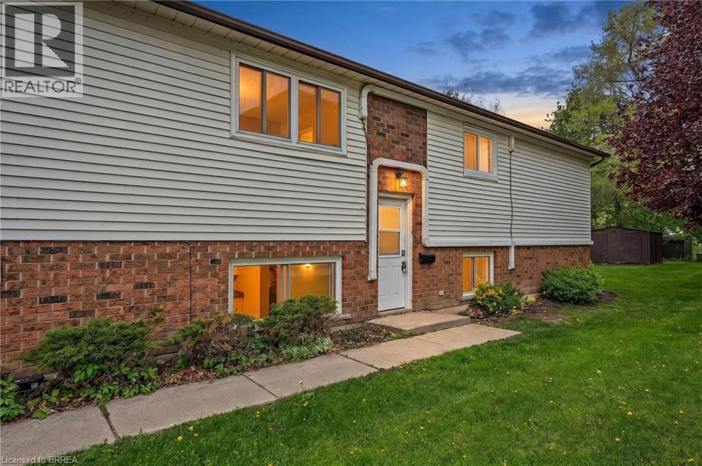 Two-story residence featuring brick and siding exterior, a front entry door with an overhead light fixture, and a concrete walkway - 9 Cherry Street, Simcoe, ON - Outdoor