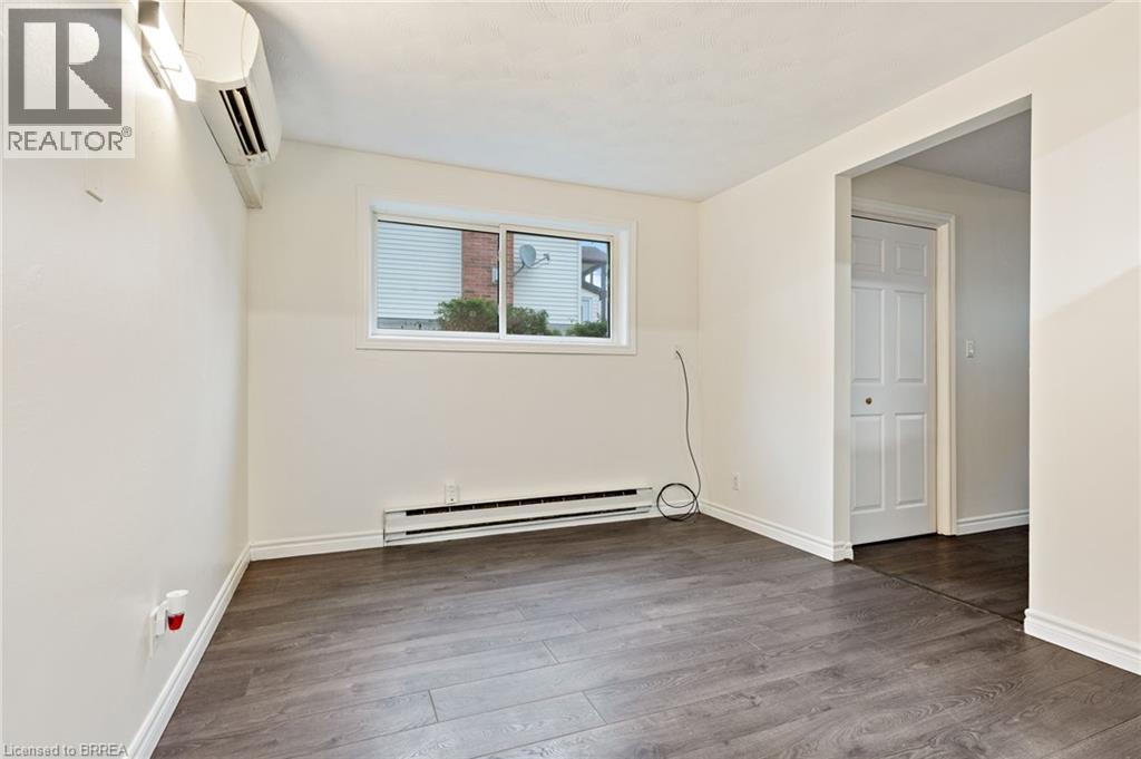 Spacious room featuring wood-finish flooring, white baseboards, and a neutral wall palette - 9 Cherry Street, Simcoe, ON - Indoor Photo Showing Other Room