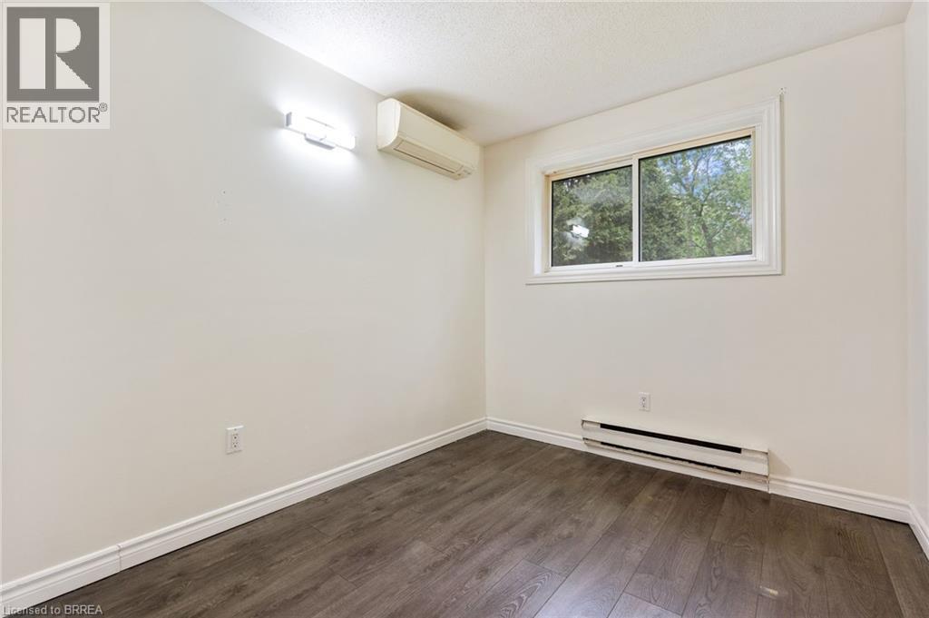 Room featuring wood-finish flooring, a white window frame, and a wall-mounted split-system unit - 9 Cherry Street, Simcoe, ON - Indoor Photo Showing Other Room