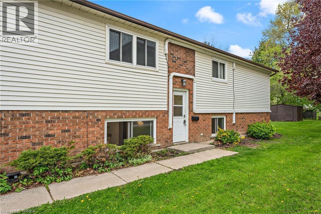 Exterior featuring brick and horizontal siding, a front entry door with an overhead light fixture, multiple windows, and a concrete walkway - 9 Cherry Street, Simcoe, ON - Outdoor