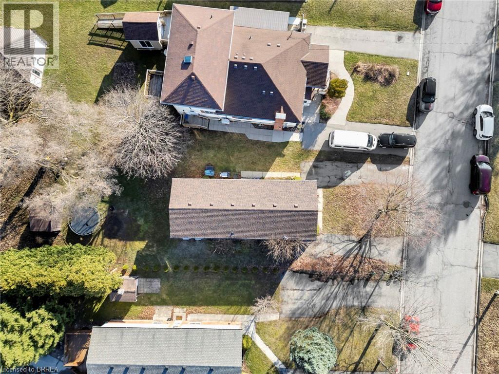Aerial perspective showcasing two distinct structures, a main residence with a multi-gabled roof and an additional long structure, both featuring brown shingle roofing - 9 Cherry Street, Simcoe, ON - Outdoor