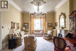 Living area featuring an ornate ceiling medallion, crystal chandelier, decorative ceiling, bay window, and a marble fireplace with a decorative mantel and hearth -