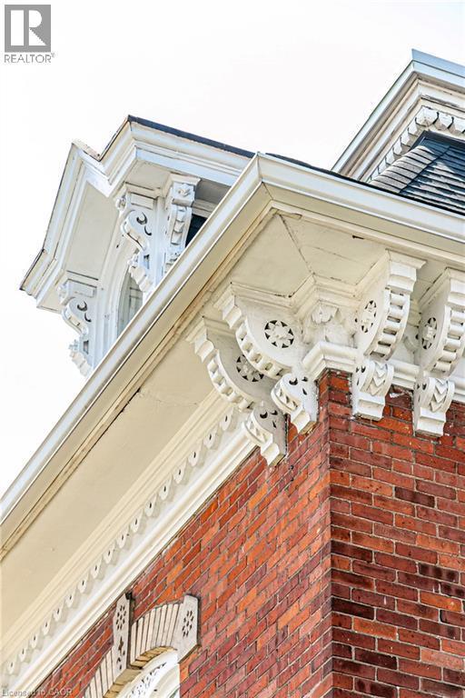 Detailed architectural elements featuring red brick construction, ornate white corbels, decorative fascia, and a prominent roofline - 370 Hess Street S, Hamilton, ON -